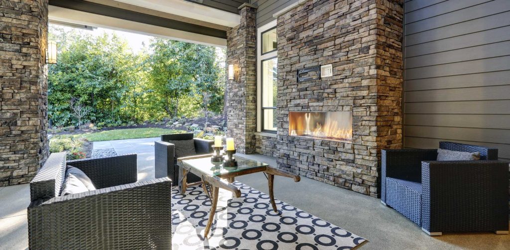 Outdoor stone fireplace beside a covered patio